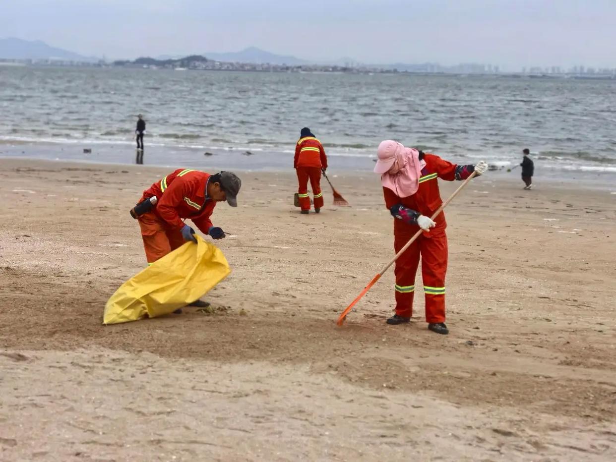 青岛一环卫工人将垃圾扫进大海