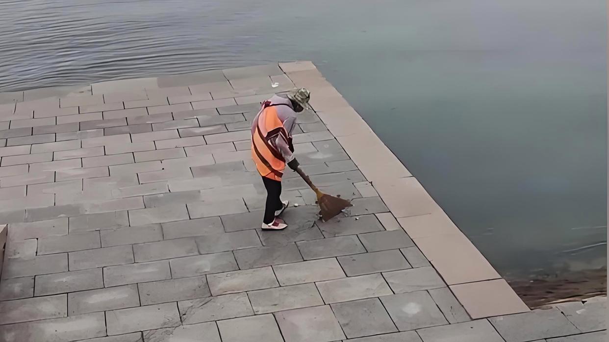 青岛一环卫工人将垃圾扫进大海